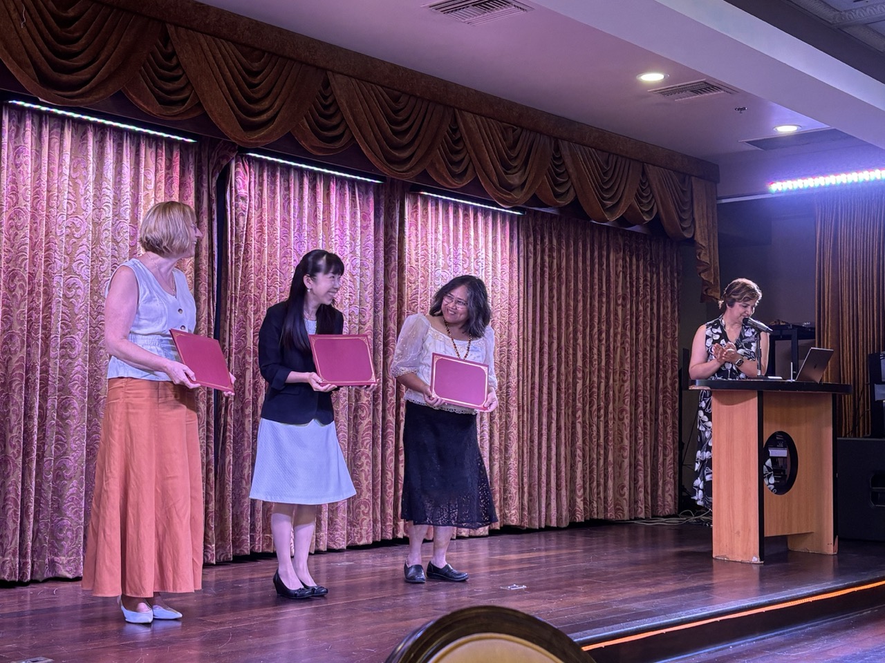 Three teachers receive ELLA award on stage, alongside SAILN director
